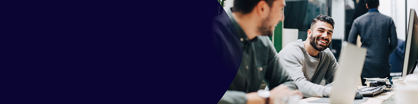 Colleagues discussing insights on a tablet while seated on colorful lounge chairs in an open workspace.